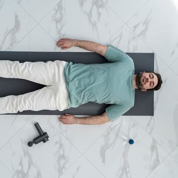 Mann liegt auf Rücken und entspannt sich mit einer progressiven Muskelrelaxation nach Jacobsen