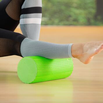 grüne Faszienrolle unter einer weiblichen Wade